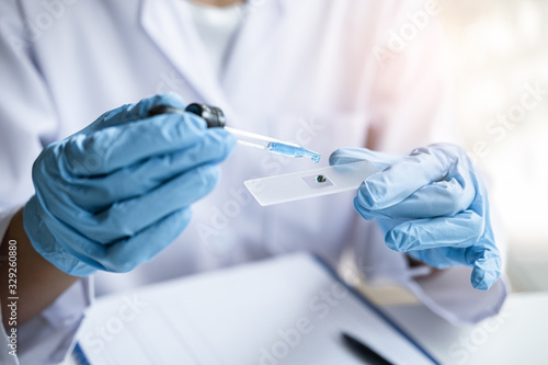 Scientist or medical in lab coat holding test tube with reagent, mixing reagents in glass flask, glassware containing chemical liquid, laboratory research and testing of Microscope