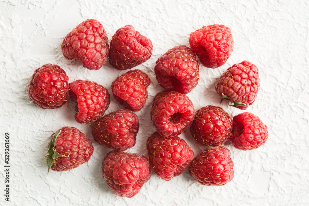 Stack of fresh red raspberries over white textured background Stack of fresh red raspberries over white textured background