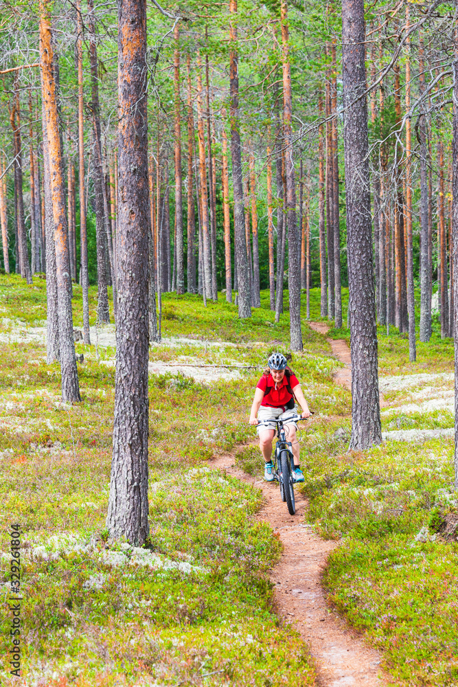 Obraz premium Woman cycling on path through woods, Rörbäcksnäs, Dalarna, Sweden