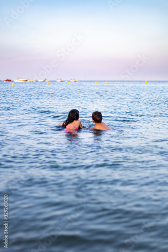 Two little kids swimming on the sea