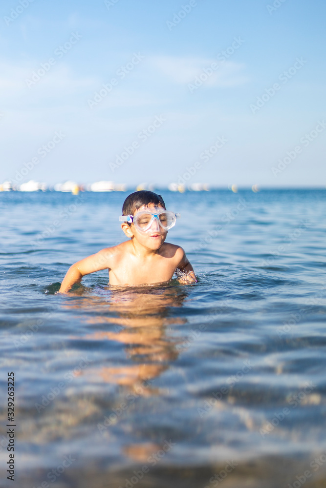 Funny kid with diving goggles on the beach