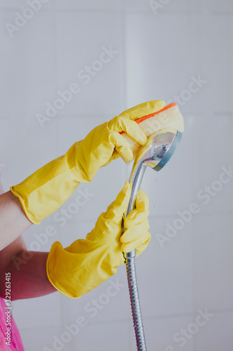 Woman in rubber gloves cleaning the shower head