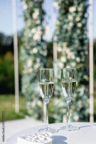 Closeup of two glasses of fresh champagne on wooden table on green background. Party and holiday celebration concept