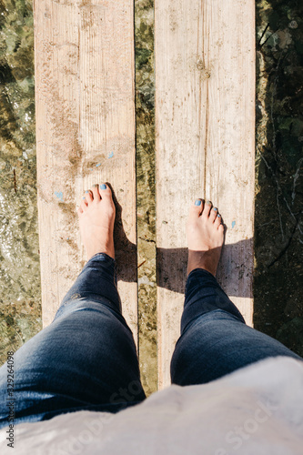 Woman walking barefoot on wooden boards over shallow sea