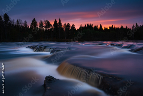 Misty water rushing over rocks at sunset, Sweden.
