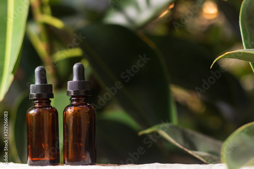 Pair of empty droppers in the foreground in front of nature background. healthy concept. medicine containers. bottles for essential oils