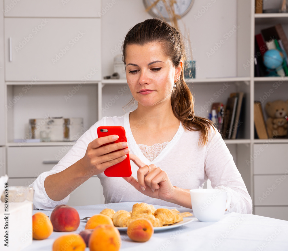 Smiling woman with phone during breakfast