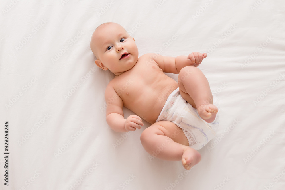 baby boy 5 months old smiling in diapers lying on the bed, top view baby boy 5 months old smiling in diapers lying on the bed, top view