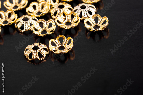 Metal jewelry accessories are scattered on a black background © kudryshanna