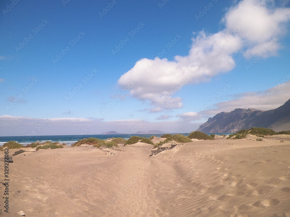 Beach and Mountains - beautiful coast in Caleta de Famara, Lanzarote Canary Islands. Beach in Caleta de Famara is very popular among surfers Beach and Mountains - beautiful coast in Caleta de Famara, Lanzarote Canary Islands. Beach in Caleta de Famara is very popular among surfers