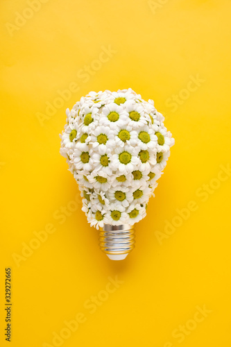 Energy Saving LED Lamp with Flowers over yellow background. Gree