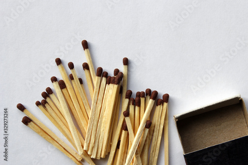 Wooden protective matches are scattered around a cardboard matchbox.