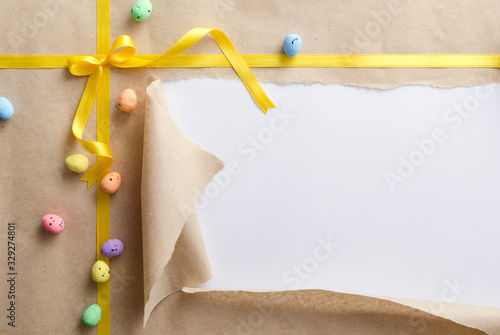 Photography Top view of decorative easter eggs on the craft wrapping paper, bright yellow bow and ribbon