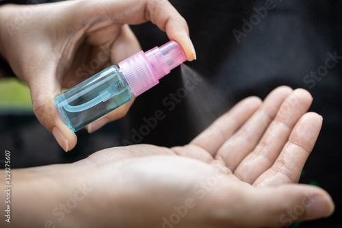 Asian woman hold a bottle of alcohol disinfectant,girl is spraying alcohol on her palms or hands to prevent infection of Covid-19 virus,contamination of germs,bacteria,cleaning,wash hands frequently