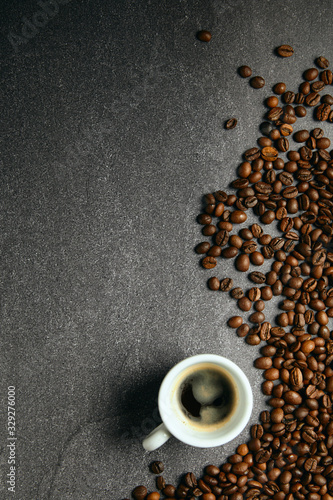 Vertical top view of coffee beans and cup, on a dark ardesia table