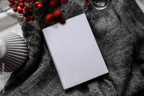 Winter autumn mock up with white book cover. Greetings card new year book mockup with red rowan berries over gray wool plaid. White book cover winter cozy mock-up.Warm festive rowan tree backdrop.