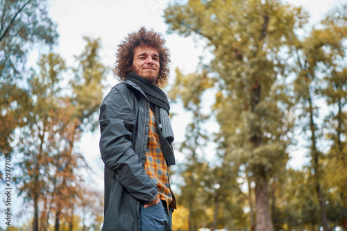 Outdoors portrait of young man with curly hair in the park.