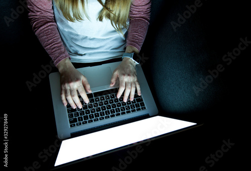 Woman works late sitting on the sofa with laptop