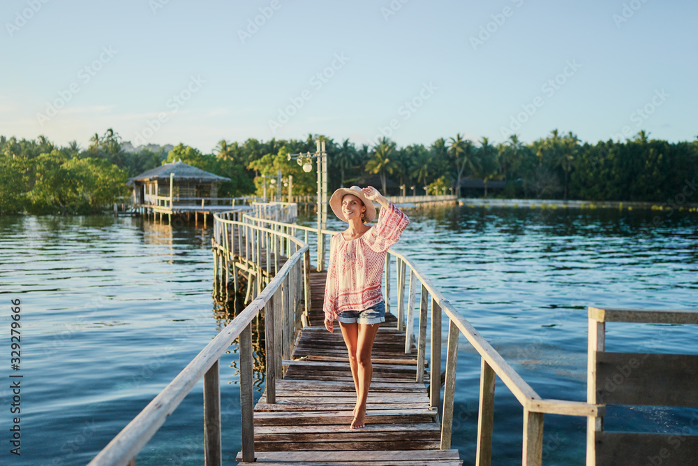 Obraz premium Vacation on tropical island. Young woman in hat enjoying sunset sea view from wooden bridge terrace, Siargao Philippines.