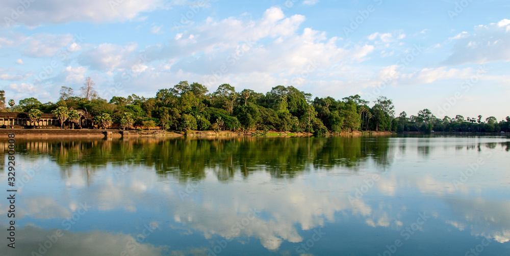 Fototapeta premium Panorama einer Seelandschaft mit sich im Wasser spiegelnden Bäumen in Angkor Wat, Kambodscha