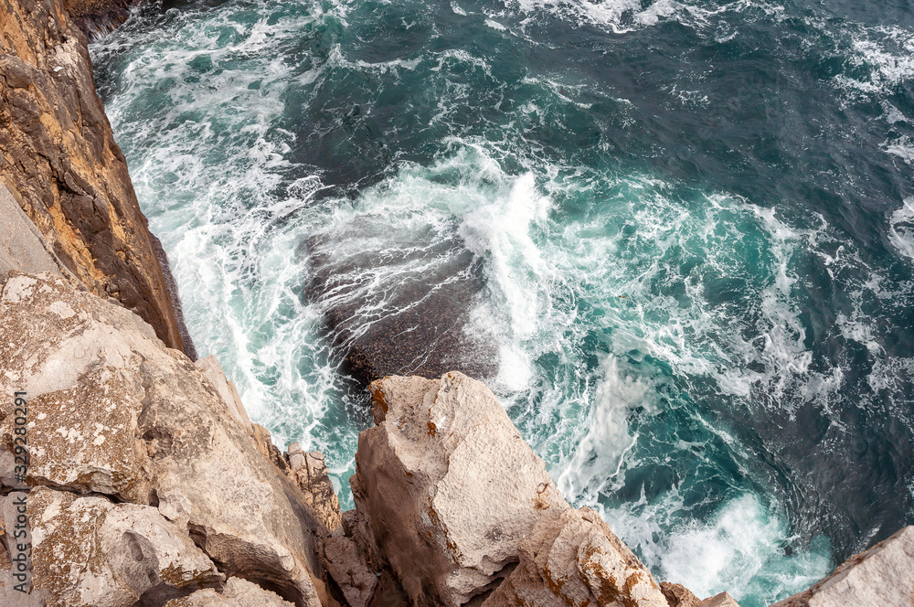 Top view photo of Atlantic ocean waves hitting rocks on the beach with turquoise sea water. Amazing rock cliff seascape in the Portuguese coastline. Peniche costline. Top view photo of Atlantic ocean waves hitting rocks on the beach with turquoise sea water. Amazing rock cliff seascape in the Portuguese coastline. Peniche costline.