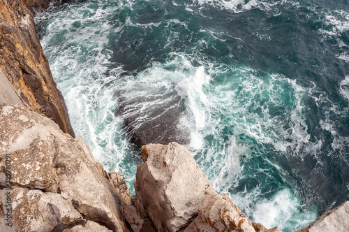 Top view photo of Atlantic ocean waves hitting rocks on the beach with turquoise sea water. Amazing rock cliff seascape in the Portuguese coastline. Peniche costline.