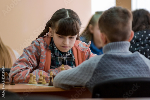 A girl plays chess. Game of chess. Tournament. A girl plays against a boy.