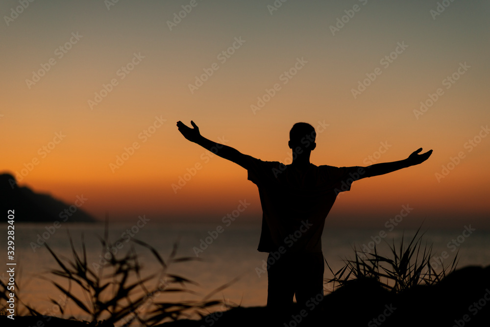 Silhouette on the Adriatic sea of a boy raising his arms