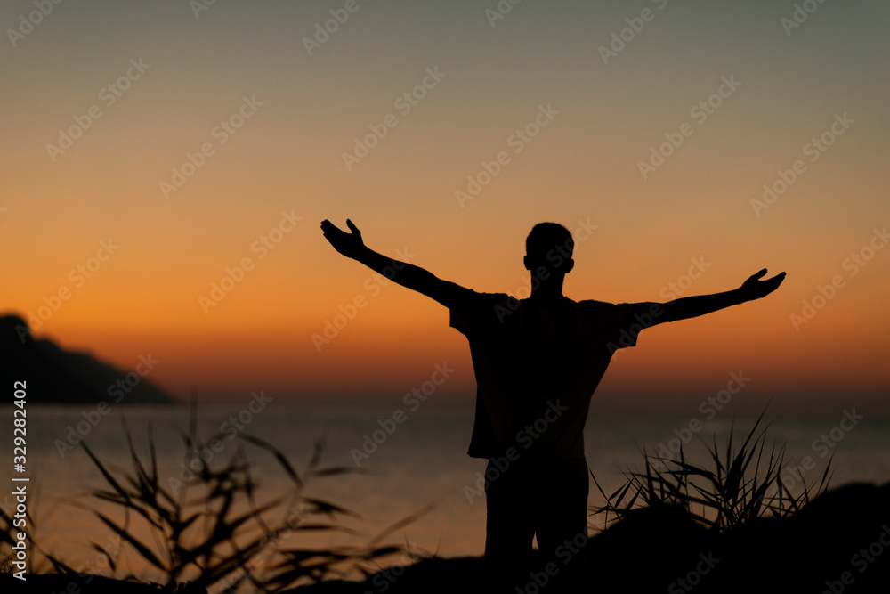 Silhouette on the Adriatic sea of a boy raising his arms Silhouette on the Adriatic sea of a boy raising his arms