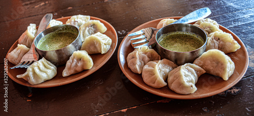 Indian kitchen. Tasty chicken momos with spicy kenza sauce on a wooden vintage background. photo