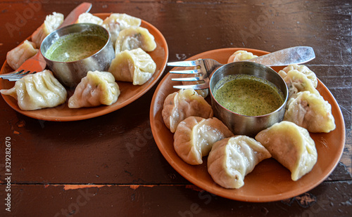 Indian kitchen. Tasty chicken momos with spicy kenza sauce on a wooden vintage background. photo