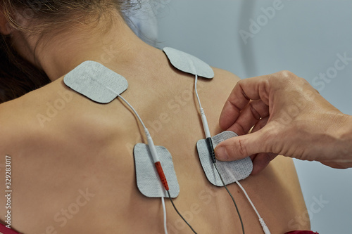 Electro stimulation in physical therapy to a young woman. Medical check at the shoulder in a physiotherapy center. Tens therapy