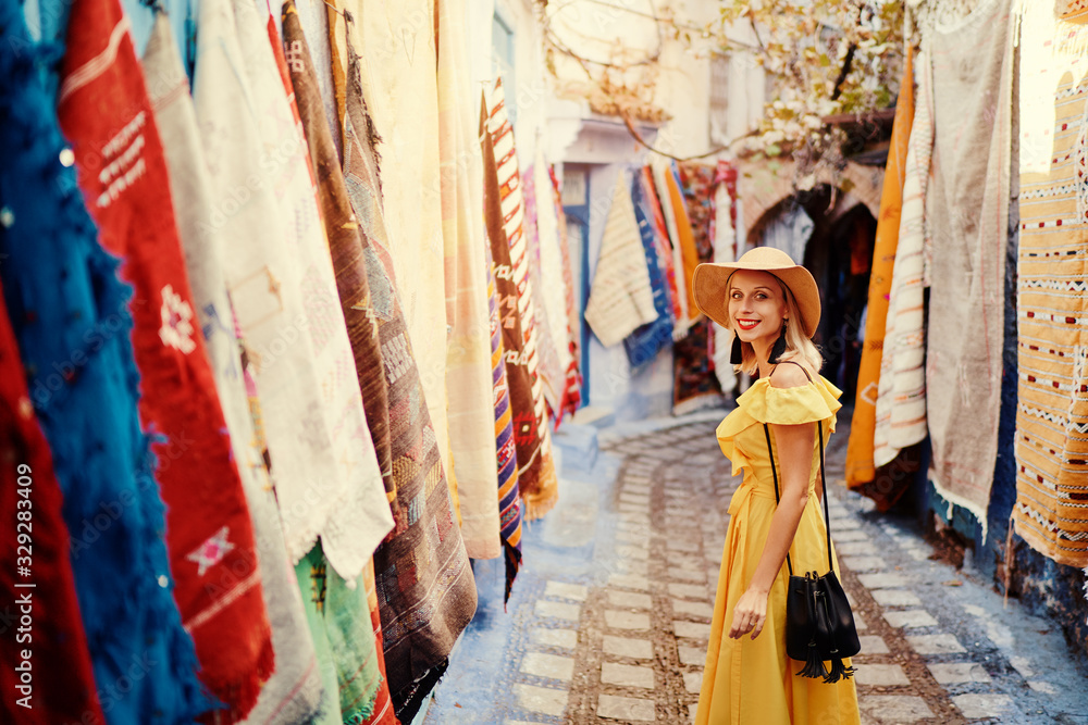 Obraz premium Colorful traveling by Morocco. Young woman in yellow dress walking in medina of blue city Chefchaouen.