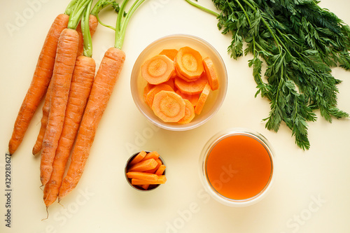 Flat lay composition with fresh carrot juice and ripe carrots on a yellow background.