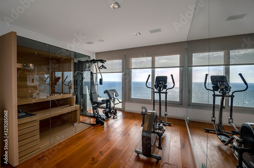 Sauna and fitness room with sea view. Traditional finnish sauna made from woodand glass door design in the sauna.  Concept of: relax, vacation, wellness center. 
