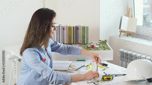 Young talented achitect using compasses while drawing a model of building. Job, profession occupation. Girl searching new ideas for construction project. photo