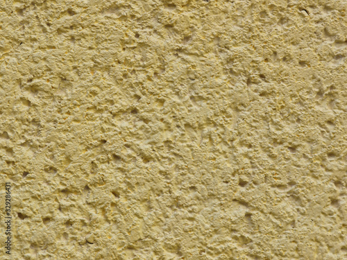 Yellow background facade plaster . Monolithic plaster decorative backdrop. Single layer scraped cement plaster wallpaper. Exterior building structure backdrop. Silica sand cement wall plaster