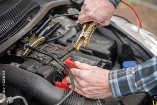 Hands of car mechanic using car battery jumper cable
