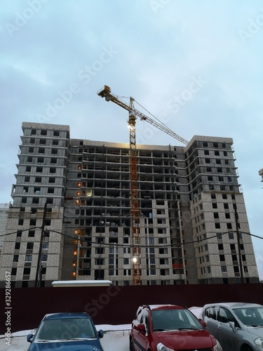 Construction crane in front of a multi storey building under construction lined with bricks
