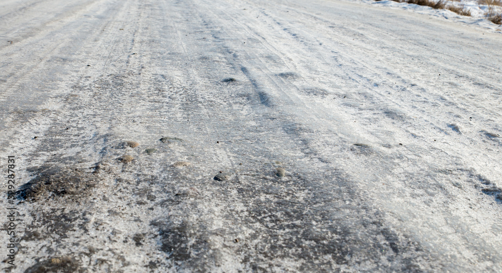 Dangerous driving conditions. Icy road with tracks from the wheels of cars . The concept of safe driving on a winter slippery track. The texture of the ice road. Dangerous driving conditions. Icy road with tracks from the wheels of cars . The concept of safe driving on a winter slippery track. The texture of the ice road.