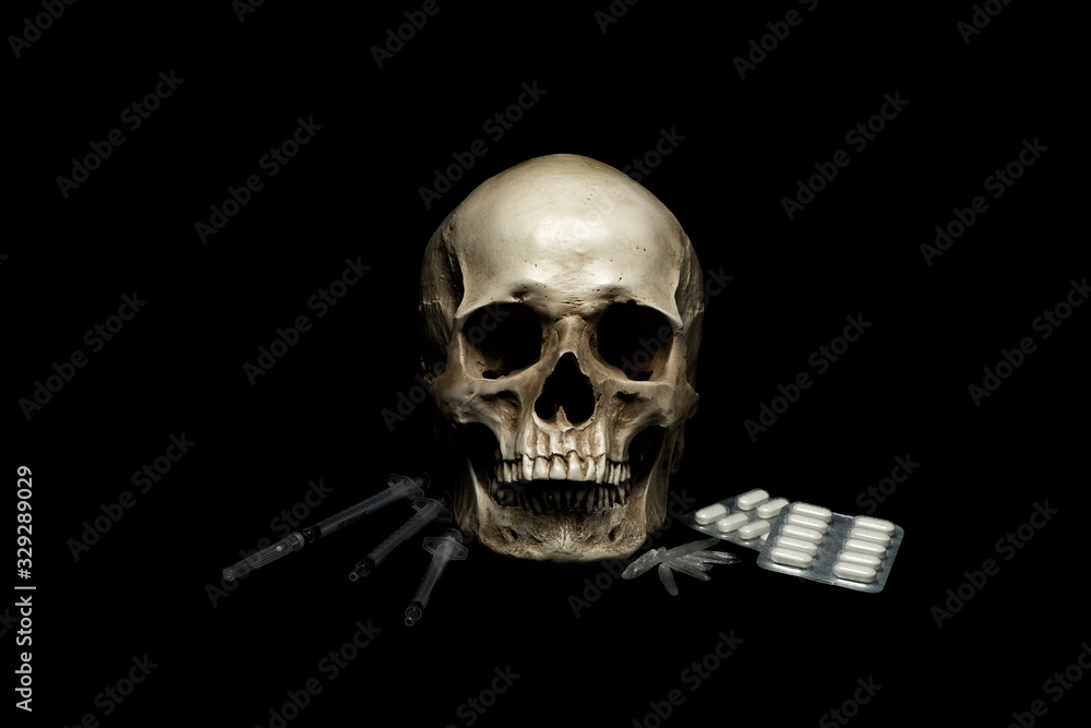 Human skull with syringre, crystals and pills on black background. Drugs and crime concept. Human skull with syringre, crystals and pills on black background. Drugs and crime concept.