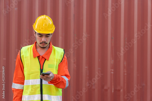 Engineer is working on Smart Phone at container yard. Industrial Container yard for Logistic Import Export business.