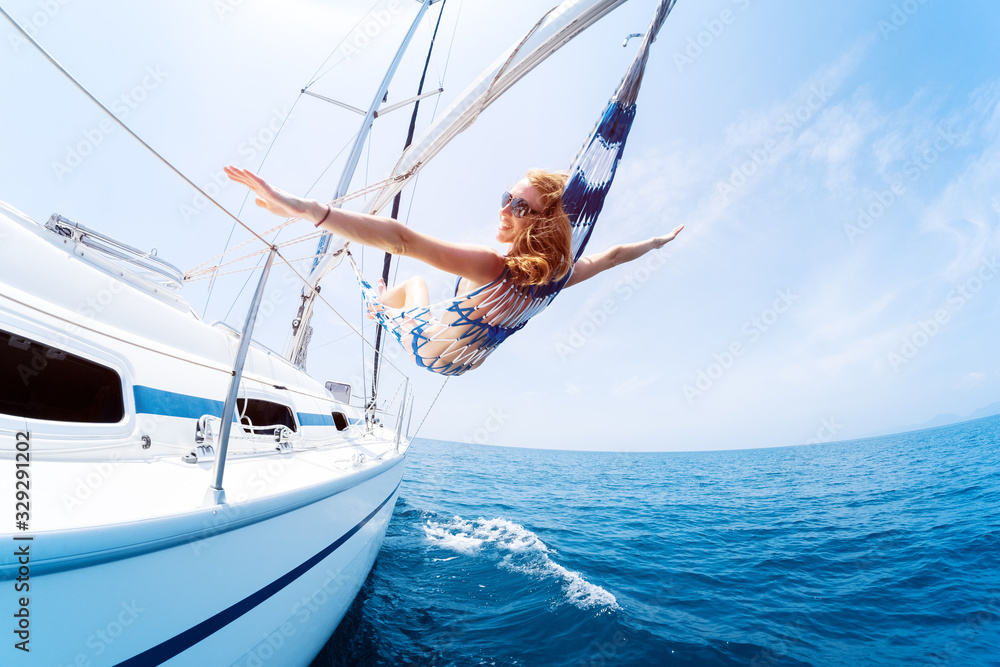 Obraz premium Young woman enjoys tropical sailing in the hammock set on the yacht