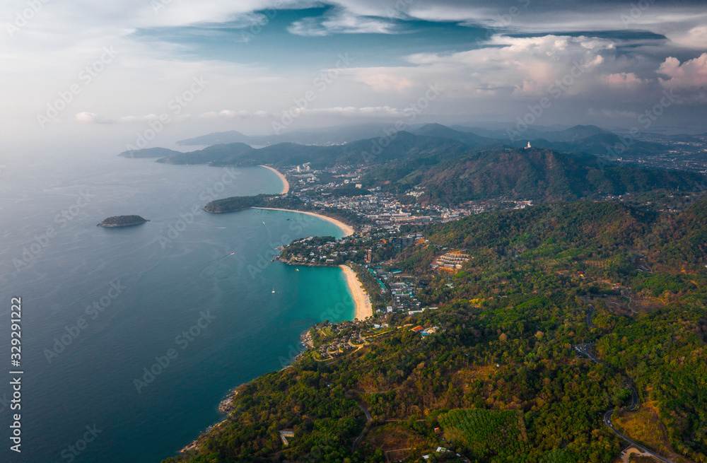 Aerial view of the coastline of Phuket island with tropical sandy beaches and mountains at sunset, Thailand