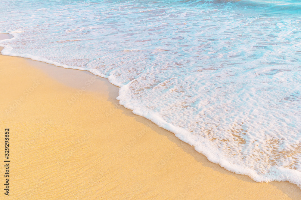 Tropical shore. Sandy beach and wavy sea in warm sunset light.