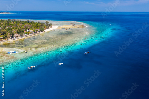 Aerial drone view of snorkelers and boats above a coral reef in a clear, tropical ocean