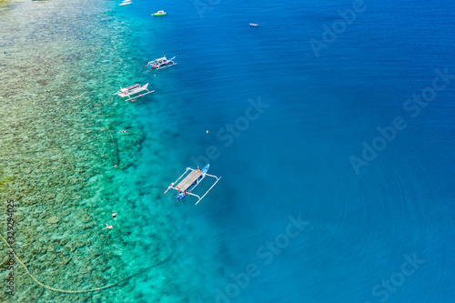 Aerial drone view of snorkelers and boats above a coral reef in a clear  tropical ocean
