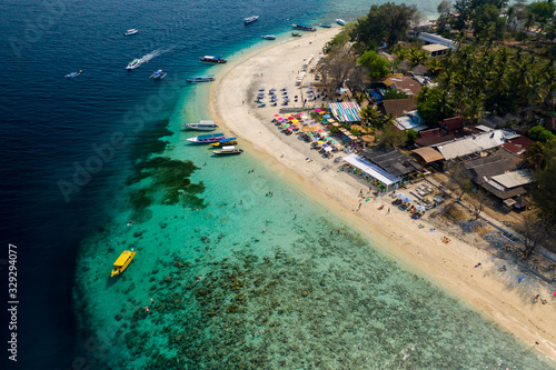 Aerial drone view of a beautiful tropical island with beach, coral reef, boats and snorkelers