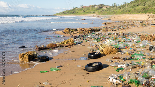 Plastic waste products and car tyres litter a beautiful sandy beach at Umkomaas in South Africa. photo