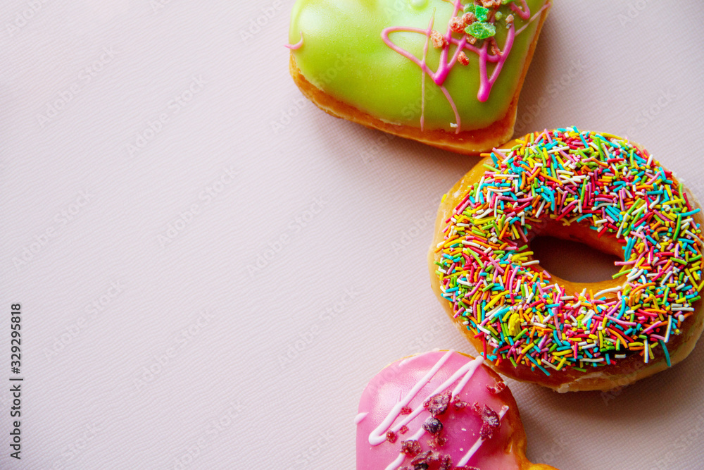 Top view of assorted donuts on pink concrete background with copy space. Colorful donuts background. Top view of assorted donuts on pink concrete background with copy space. Colorful donuts background.